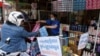 FILE - A vendor shows sachets of hair shampoo to a customer from a shop that has been marked off to allow for social distancing, as a preventive measure against the spread of the COVID-19 novel coronavirus, in Phnom Penh, May 27, 2020. 