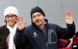 FILE - U.S. journalist Jason Rezaian gestures next to his wife Yeganeh Salehi as he poses for media people in front of Landstuhl Regional Medical Center in Landstuhl, Germany, Jan. 20, 2016.