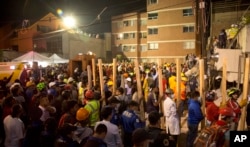 FILE - Volunteers bring pieces of wood to help prop up sections of the collapsed Enrique Rebsamen school, as rescue workers search for children trapped inside, in Mexico City, Sept. 19, 2017.
