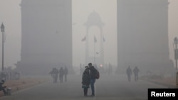 FILE - People take a selfie in front of the India Gate war memorial on a smoggy winter morning in New Delhi, India, Dec. 26, 2017.