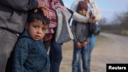 Una familia de migrantes, procedentes de Honduras, aguarda a que pase un vehículo tras haber entrado en Estados Unidos cruzando el Rio Grande, el 6 de marzo de 2021.