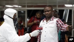 A Nigerian port health official uses a thermometer on a worker at the arrivals hall of Murtala Muhammed International Airport in Lagos, Nigeria, Wednesday, Aug. 6, 2014.