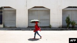 Seorang perempuan menggunakan payung untuk berlindung dari terik matahari saat cuaca panas di Manila pada 28 April 2024. (Foto: AFP)