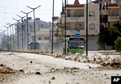 FILE - Syrian government buses evacuate residents from Al-Waer, the last rebel-held neighborhood of Homs, Syria, Thursday, Sept. 22, 2016.