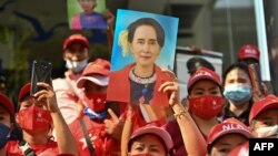 Myanmar migrants hold up portraits of detained leader Aung San Suu Kyi as they rally outside Myanmar's embassy in Bangkok, Thailand, Feb. 1, 2021.