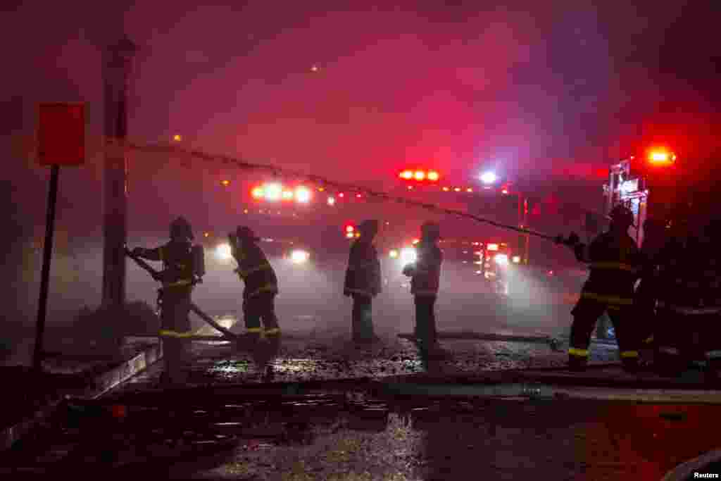 Baltimore city firefighters spray water on a residence which was set ablaze in west Baltimore after the funeral of Freddie Gray in Maryland, April 28, 2015. 