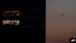 FILE - A passenger plane flies over Beirut, Lebanon, a capital in darkness because of a power outage, March 29, 2021.