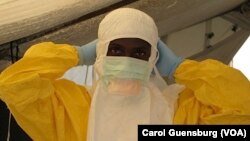 A health worker adjusts protective gear at a Doctors Without Borders' Ebola treatment unit in Conakry, Guinea. (VOA / Carol Guensburg) 