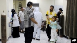 In this May 12, 2020 photo, Yemeni medical workers wearing masks and protective gear talk to patients at hospital in Aden, Yemen.