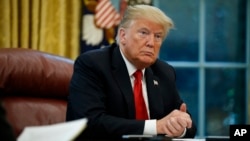 FILE - President Donald Trump listens to a question during an interview in the Oval Office of the White House, in Washington, Oct. 16, 2018.
