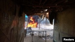 FILE - A fire is seen burning in a street during protests against price increases in Atbara, Nile River state, northeastern Sudan, Dec. 20, 2018.