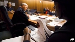 In this Aug. 30, 2017, photo, Stephanie Pope-Earley, right, sorts through defendant files scored with risk-assessment software for Jimmy Jackson Jr., a municipal court judge, on the first day of the software's use in Cleveland. (AP Photo/Dake Kang)