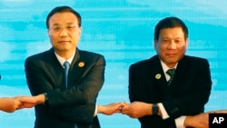 In this Sept. 7, 2016, photo, Chinese Premier Li Keqiang (L) and Philippine President Rodrigo Duterte link arms during the ASEAN Plus Three summit in Vientiane, Laos.