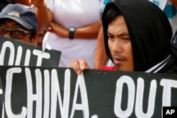 FILE - Protesters hold placards during a rally outside the Chinese Consulate in Manila to protest China's artificial island-building at the disputed islands, reefs and shoals off South China Sea, June 12, 2017.