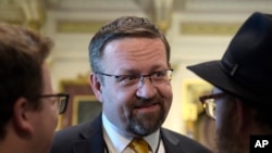 FILE - Sebastian Gorka, then a deputy assistant to President Donald Trump, talks with people in the Treaty Room in the Eisenhower Executive Office Building on the White House complex in Washington, May 2, 2017.