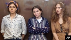 August 3, 2012: Pussy Riot members, from left, Nadezhda Tolokonnikova, Yekaterina Samutsevich and Maria Alekhina sit in a glass cage at a court room in Moscow, Russia. 
