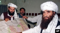 A 2001 file photo of Jalaluddin Haqqani (R), Leader of the Haqqani Network, pointing to a map of Afghanistan during a visit to Islamabad, Pakistan while his son Naziruddin (L) looks on