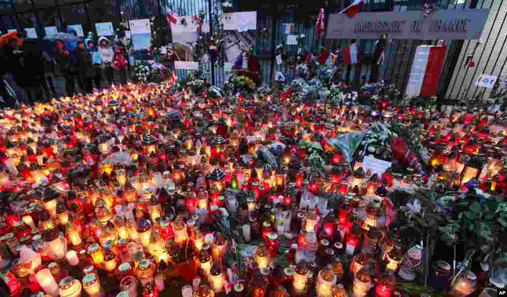 People place flowers and light candles for the victims of the deadly attacks in Paris, outside the French Embassy in Warsaw, Poland, Nov. 15, 2015.