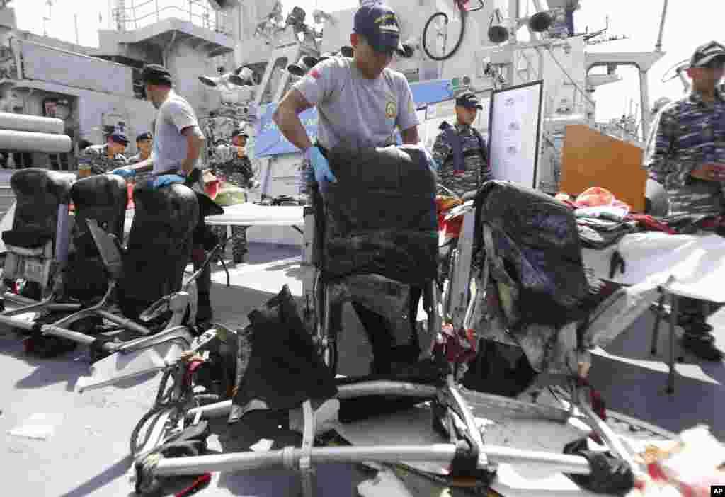 Crew members of Indonesian Navy ship KRI Bung Tomo show airplane seats from AirAsia Flight 8501 recovered in search operations for the ill-fated jetliner, during a press conference at the Navy's Eastern Fleet Naval Base in Surabaya, East Java, Indonesia, Jan. 5, 2014.