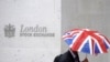 Seorang pekerja berlindung di bawah payung dengan motif bendera Inggris (Union Flag) saat melewati Bursa Efek London di London, Inggris, 1 Oktober 2008. (REUTERS/Toby Melville)