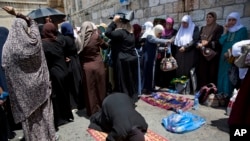 Palestinians women pray at the Lion's Gate following an appeal from clerics to pray in the streets instead of inside the Al Aqsa Mosque compound, in Jerusalem's Old City, Tuesday, July 25, 2017.