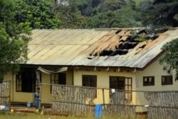 FILE - A woman stands outside a damaged school dormitory after it was set on fire in Bafut, in the northwest English-speaking region of Cameroon, Nov. 15, 2017.