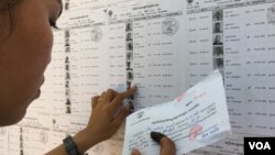 កញ្ញា​​​ជិន​​​ ស្រី​​​ធុច​​​ អាយុ​​​១៨​​​ឆ្នាំ ​​​សកម្មជន​​​របស់​​​គណបក្ស​​​សង្គ្រោះជាតិ​​​ កំពុង​​​រក​​​ឈ្មោះ ​​​និង​​​លេខរៀង​​​របស់​​​អ្នក​​​បោះឆ្នោត​​​នៅ​​​ក្នុង​​​ឃុំ​​​ដំដែក​​​ស្រុក​​​សូត្រ​​​និគម​​​នៅ​​​ការិយាល័យ​​​បោះឆ្នោត​​ក្នុង​​​វិទ្យាល័យ​​​ដំដែក។ (ផន បុប្ផា/VOA)