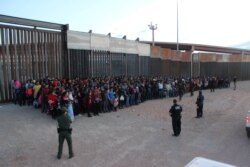 FILE - U.S. Border Patrol agents keep watch on a large group of migrants who they say were attempting to cross the U.S.-Mexico border illegally, in El Paso, Texas, May 29, 2019.