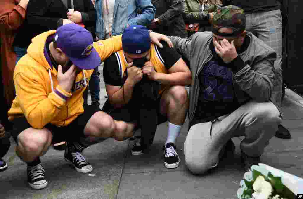 Los Angeles Laker fans Alex Fultz, from left, Eddy Rivas and Rene Alfaro mourn retired NBA star Kobe Bryant outside of the Staples Center in Los Angeles, Jan. 26, 2020.