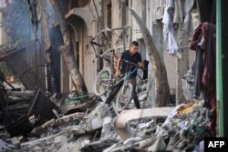 Seorang anak laki-laki Palestina membawa sepedanya sehari setelah operasi Pasukan Khusus Israel di Kamp Nuseirat, di Jalur Gaza tengah pada 9 Juni 2024. (Foto: AFP)