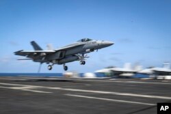 FILE - An F/A-18E Super Hornet lands on the flight deck of the Nimitz-class aircraft carrier USS Abraham Lincoln in the Arabian Sea, May 20, 2019.