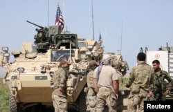 FILE - Kurdish fighters from the People's Protection Units (YPG) chat with members of U.S. forces in the town of Darbasiya next to the Turkish border, Syria, April 29, 2017.