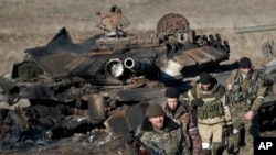 FILE - Russia-backed separatists walk after inspecting destroyed Ukrainian army tanks for functional weapons and ammunition near the village of Lohvynove, outside Debaltseve, Ukraine, Feb. 22, 2015.