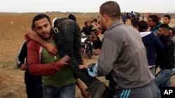 Palestinian protesters evacuate a wounded youth during clashes with Israeli troops along Gaza's border with Israel, east of Beit Lahiya, Gaza Strip, April 3, 2018.