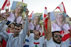 FILE - Lebanese protesters carry posters of prominent anti-Syrian news anchor May Chidiac, who was seriously wounded by a car bomb, during a sit-in at Martyrs square in Beirut, Sept. 26, 2005.