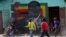 Children play soccer next to a defaced portrait of former Zimbabwean President Robert Mugabe in Harare, Sept, 6 2019.