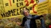 A woman holds a board that reads in French: 'One billion for Notre Dame! Zero for homeless' next to a banner that read also in French: 'One billion in 24 hours! Homeless Zero' during a protest in front of the Notre Dame cathedral in Paris, April 22, 2019.