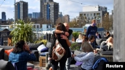 People hug at the Skylight rooftop bar as the coronavirus disease (COVID-19) restrictions ease, in London, Britain April 12, 2021. (REUTERS/Dylan Martinez)