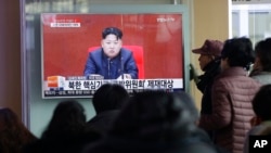 People at Seoul Railway Station in Seoul, South Korea, watch a TV news program showing North Korean leader Kim Jong Un, March 3, 2016.