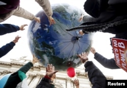 Protesters throw up a globe-shaped balloon during a rally held the day before the start of the 2015 Paris World Climate Change Conference, known as the COP21 summit, in Rome, Italy, November 29 2015.