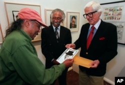 Artist and cartoonist Hank Ketcham (R) shows jazz pianist Horace Silver (L) his sketch of him as jazz composer Gerald Wilson looks on, in Los Angeles, April 17, 1999.