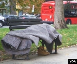 Seorang tunawisma tidur berbalut selimut di bangku taman kota Washington DC. Banyak tunawisma di AS tewas akibat hipotermia pada musim dingin.