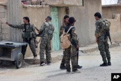 FILE -- A photo provided by the Syrian Democratic Forces (SDF) shows fighters from the SDF looking toward the northern town of Tabqa, Syria, April 30, 2017.