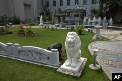 A man pulls weeds on the lawn at a garden of the Mansudae Art Studio in Pyongyang, North Korea, June 20, 2013.