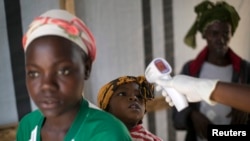 FILE - A health worker checks the temperature of a girl at the entrance to a Red Cross facility in the town of Koidu, Sierra Leone.
