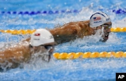 United States' Michael Phelps, top, and Singapore's Joseph Schooling compete during a men's 100-meter butterfly heat during the swimming competitions at the 2016 Summer Olympics, Aug. 11, 2016, in Rio de Janeiro, Brazil.