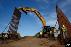FILE - Construction crews install new border wall sections, Jan. 9, 2019, seen from Tijuana, Mexico.