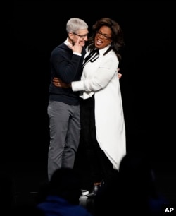 Apple CEO Tim Cook and Oprah Winfrey embrace at the Steve Jobs Theater during an event to announce new Apple products Monday, March 25, 2019, in Cupertino, Calif. (AP Photo/Tony Avelar)