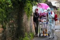 Para tenaga kesehatan dengan mengenakan alat pelindung diri membawa pasien Covid-19 di tengah pandemi virus corona di Jakarta, 13 Desember 2020. (Foto: Antara Foto/Fsauzan via Reuters)