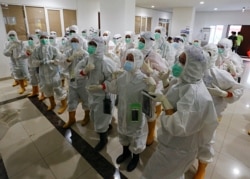 Petugas kesehatan yang mengenakan alat pelindung diri (APD) bersiap untuk merawat pasien di rumah sakit darurat COVID-19 di Wisma Atlet, Jakarta, 26 Januari 2021. (REUTERS/Ajeng Dinar Ulfiana)